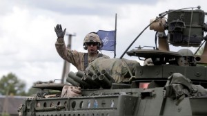 U.S. soldier waves as he crosses Lithuanian-Latvian border during tactical road march Dragoon Ride II in Subate